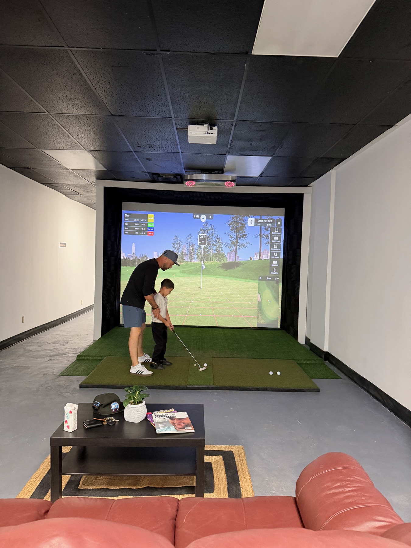 Adult helping a young golfer use the simulator at Dev's Golf Sim
